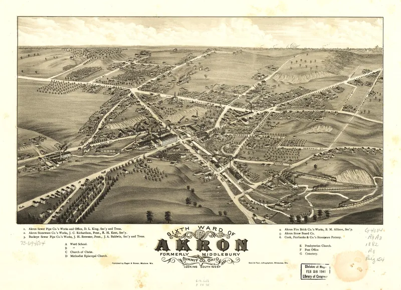 A bird's-eye drawing of a small industrial village with roads meeting at a crossroads, scattered houses and orchards, and factory buildings along a railroad, with a numbered key to the works below.
