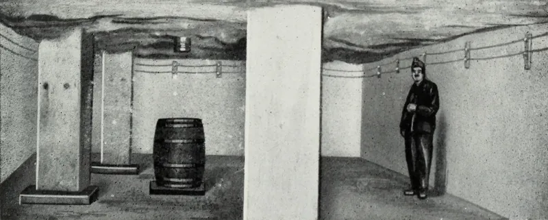 An underground room with whitewashed concrete walls and pillars under a rough rock roof, a wooden barrel on a platform, wires along the wall, and a miner in a cap standing at right.
